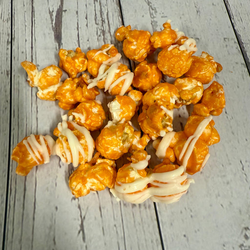 orange popcorn with white drizzle on a wooden surface