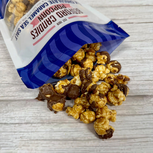 Bag of chocolate-covered popcorn spilling out onto a light wooden surface