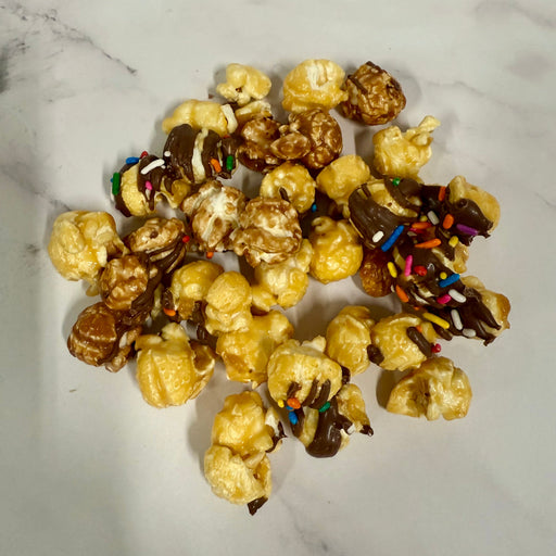 Dessert popcorn with chocolate and sprinkles on a marble surface